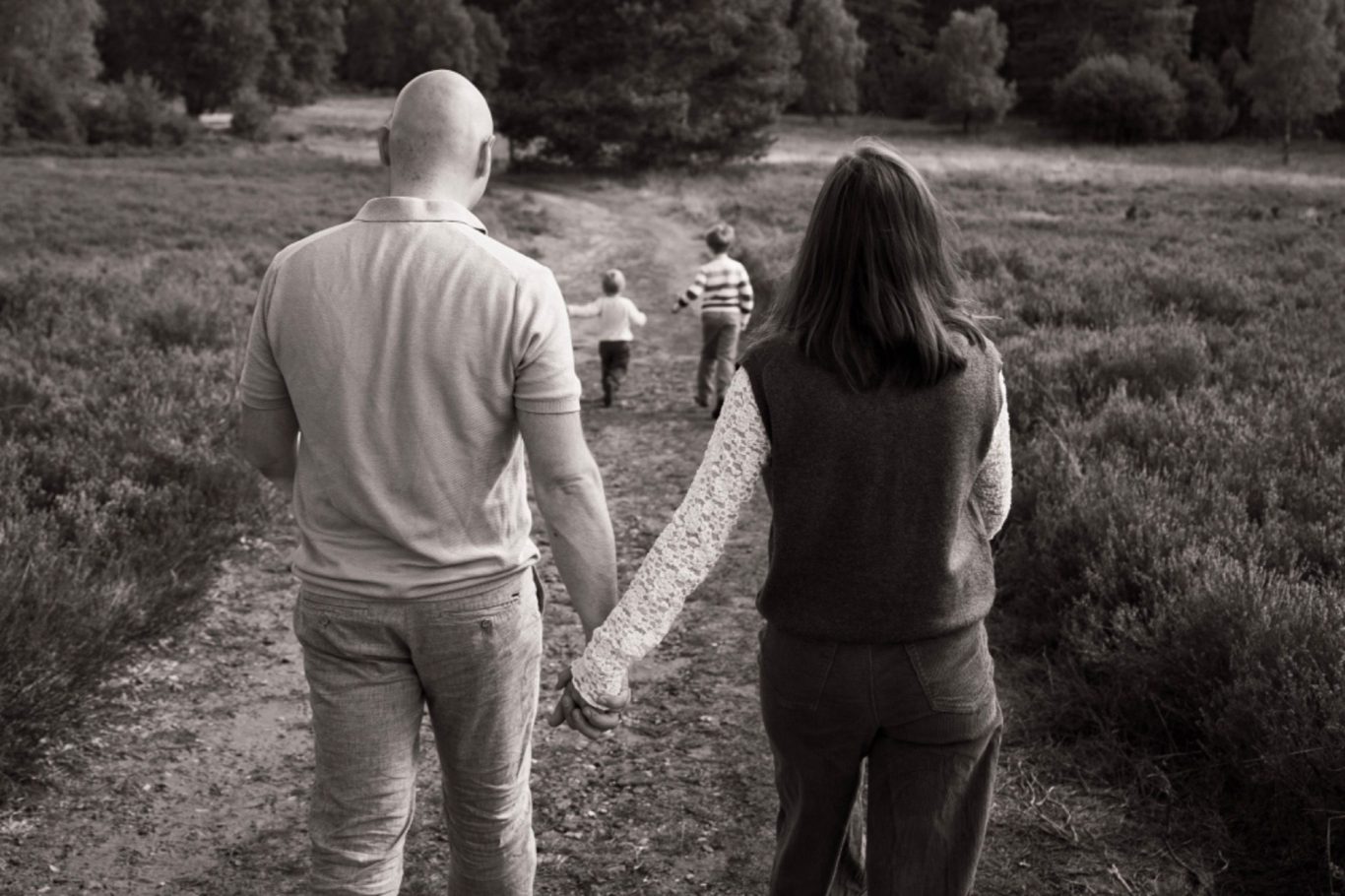 Familienfotografie Ein Paar hält zwei Kinder kopfüber und lacht dabei. Freundliche, familiäre Atmosphäre.