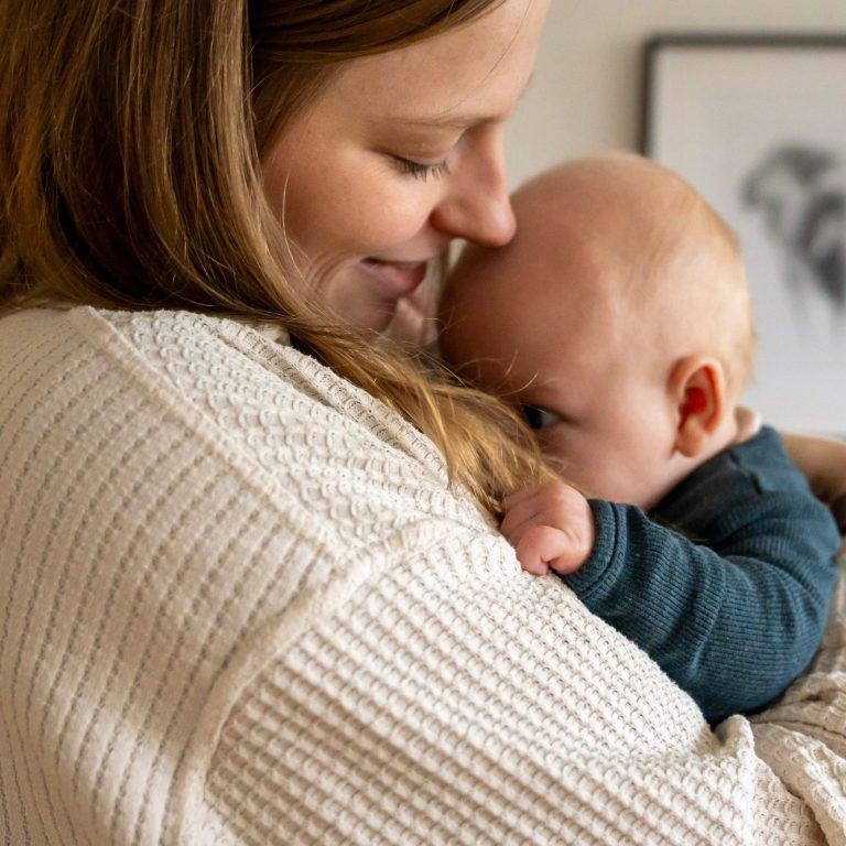 Eine Mutter hält ihr lächelndes Baby eng an sich.