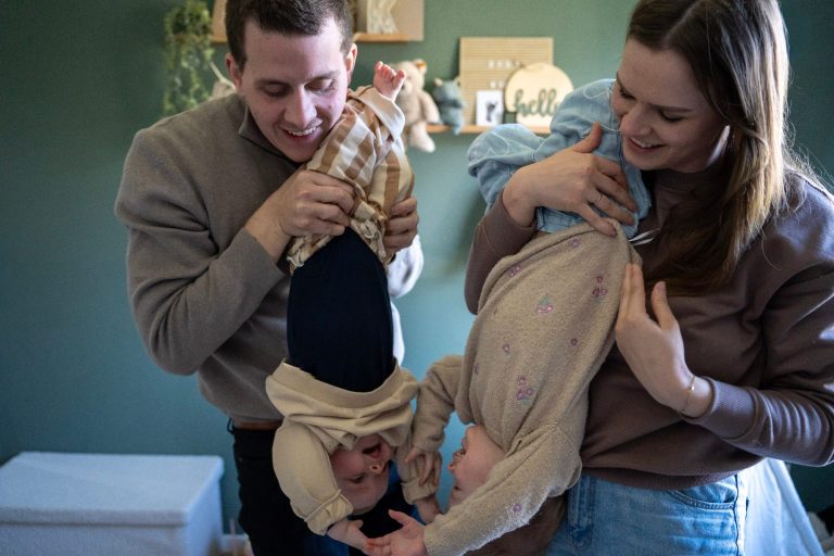 Ein Paar hält zwei Kinder kopfüber und lacht dabei. Freundliche, familiäre Atmosphäre.